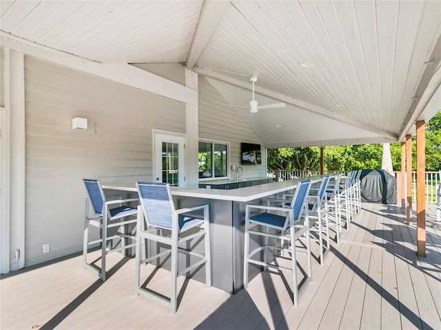 wooden deck featuring area for grilling, a ceiling fan, and outdoor wet bar