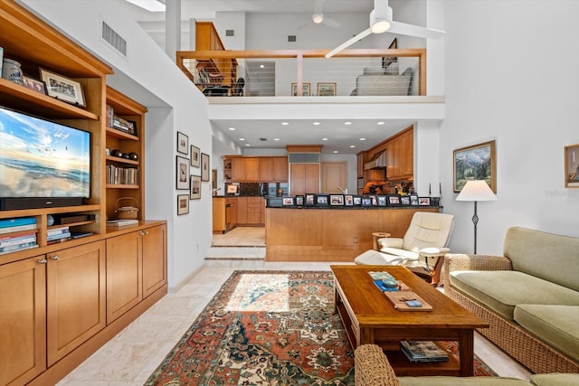 tiled living room with ceiling fan and a high ceiling