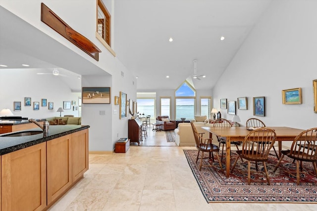 dining area with ceiling fan, sink, and high vaulted ceiling