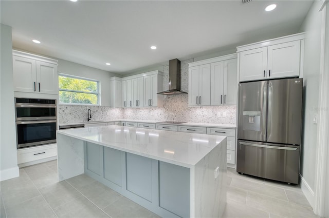 kitchen featuring stainless steel appliances, backsplash, light tile patterned floors, wall chimney range hood, and a kitchen island