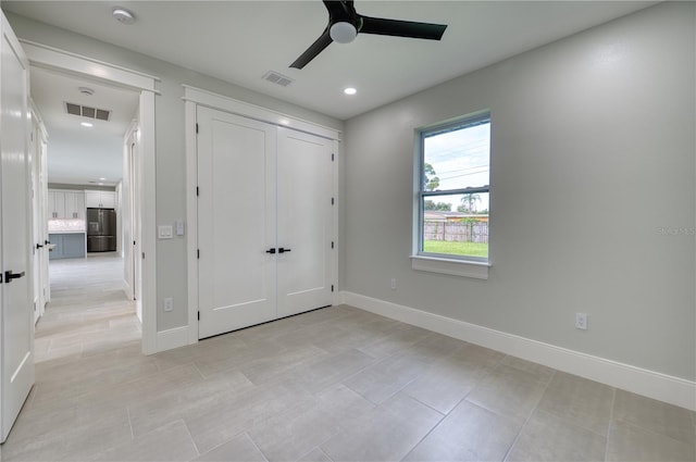 unfurnished bedroom featuring stainless steel refrigerator, light tile patterned floors, a closet, and ceiling fan