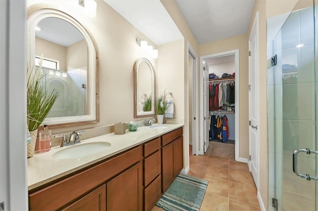 bathroom with a shower with door, dual bowl vanity, and tile patterned floors