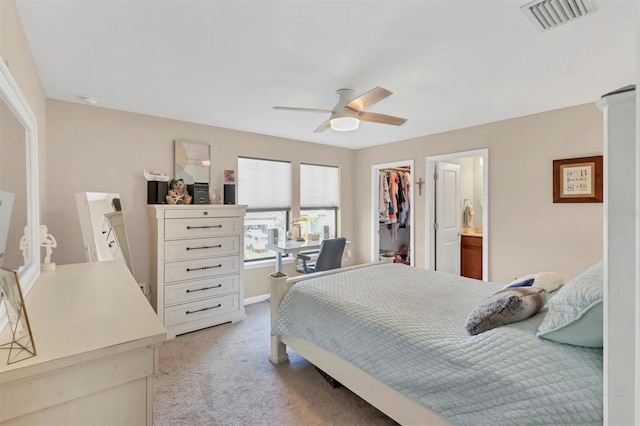 bedroom featuring ceiling fan, light carpet, a closet, and a walk in closet