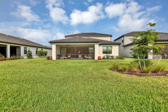 rear view of house featuring a sunroom and a lawn