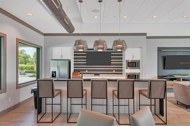 kitchen with a breakfast bar, hanging light fixtures, light tile patterned floors, stainless steel appliances, and white cabinets