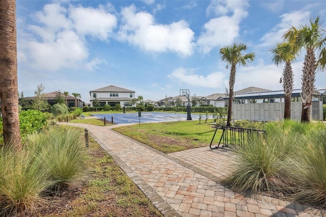 view of home's community with a lawn, mail boxes, and basketball hoop