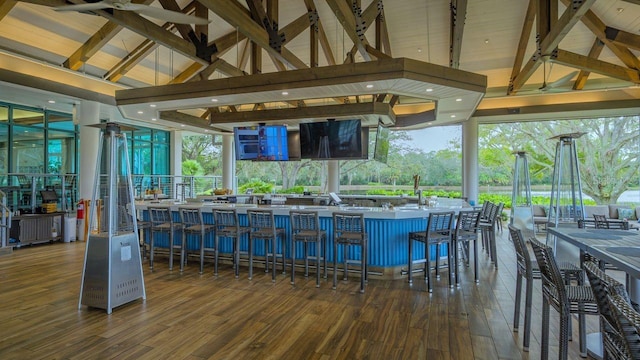 bar with dark hardwood / wood-style floors, beam ceiling, and high vaulted ceiling