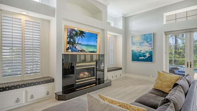 living room featuring crown molding, french doors, a towering ceiling, and light hardwood / wood-style floors