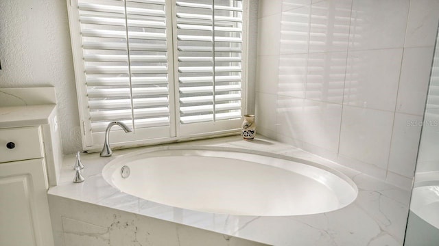 bathroom featuring vanity and tiled bath