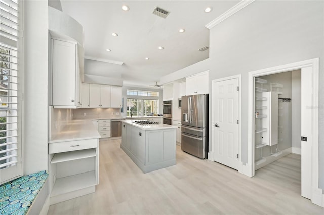 kitchen with tasteful backsplash, white cabinetry, a kitchen island, and stainless steel appliances