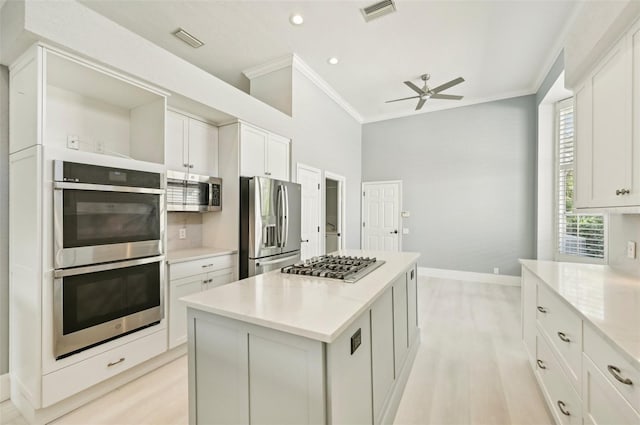 kitchen featuring light stone countertops, appliances with stainless steel finishes, ceiling fan, white cabinets, and a center island