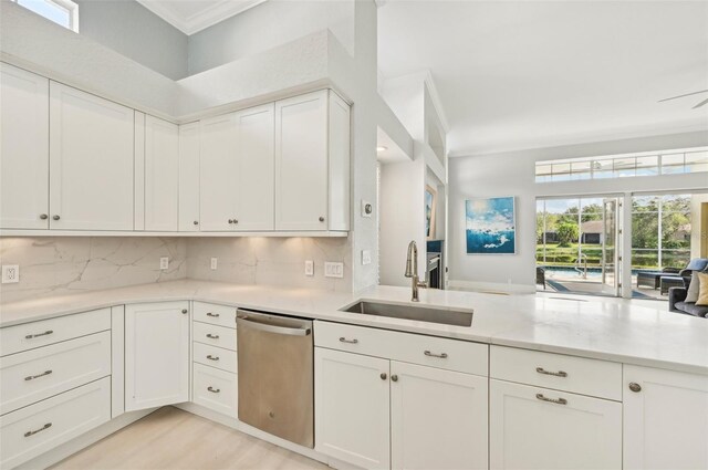 kitchen with sink, stainless steel dishwasher, tasteful backsplash, white cabinetry, and kitchen peninsula