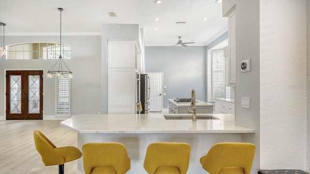 kitchen featuring pendant lighting, a breakfast bar, sink, and french doors