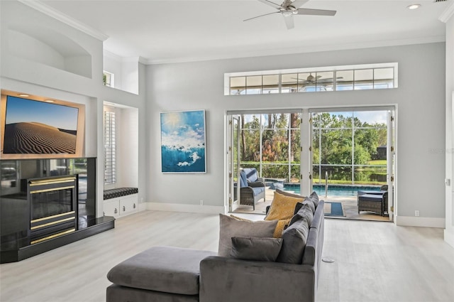 living room with light hardwood / wood-style flooring, ceiling fan, and ornamental molding