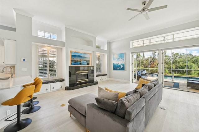 living room featuring sink, plenty of natural light, a tile fireplace, and ornamental molding