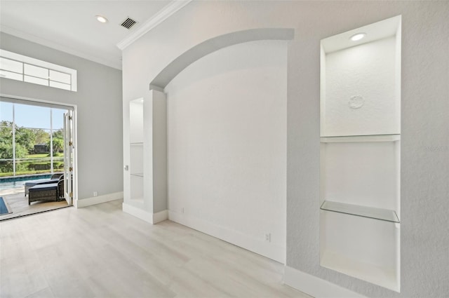 empty room with ornamental molding and light wood-type flooring