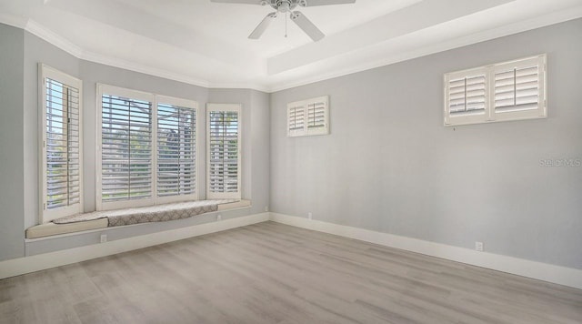 spare room with ceiling fan, ornamental molding, a tray ceiling, and light hardwood / wood-style flooring