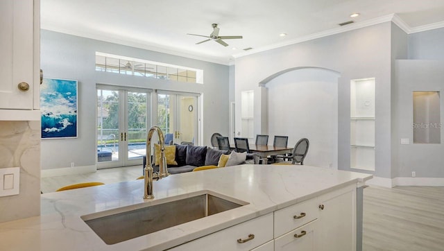 kitchen featuring sink, white cabinets, light stone counters, crown molding, and french doors