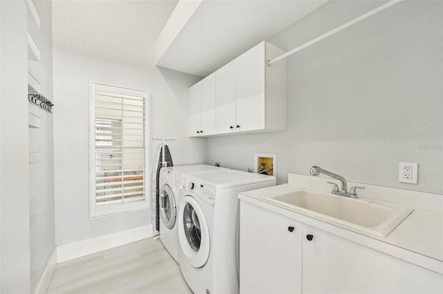 clothes washing area featuring cabinets, washer and dryer, sink, and light hardwood / wood-style flooring