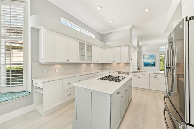 kitchen featuring white cabinetry, a center island, appliances with stainless steel finishes, a wealth of natural light, and decorative backsplash