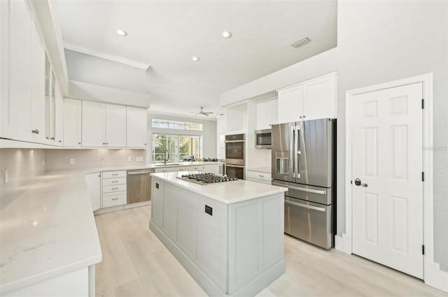 kitchen featuring sink, white cabinetry, light stone counters, a center island, and stainless steel appliances