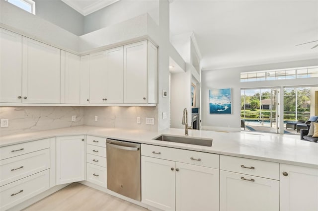 kitchen with sink, crown molding, dishwasher, white cabinetry, and backsplash