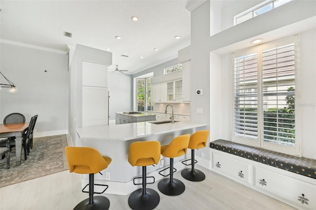 kitchen featuring sink, crown molding, white cabinetry, a kitchen bar, and kitchen peninsula