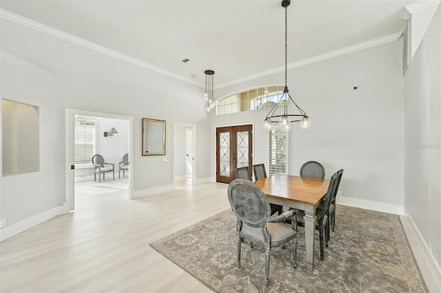 dining room featuring french doors, ornamental molding, an inviting chandelier, and light hardwood / wood-style flooring