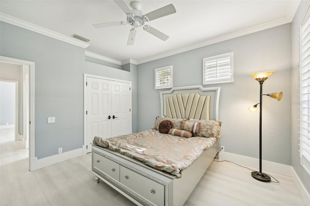 bedroom with a closet, ornamental molding, light hardwood / wood-style floors, and ceiling fan