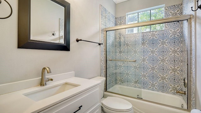 full bathroom with vanity, bath / shower combo with glass door, and toilet