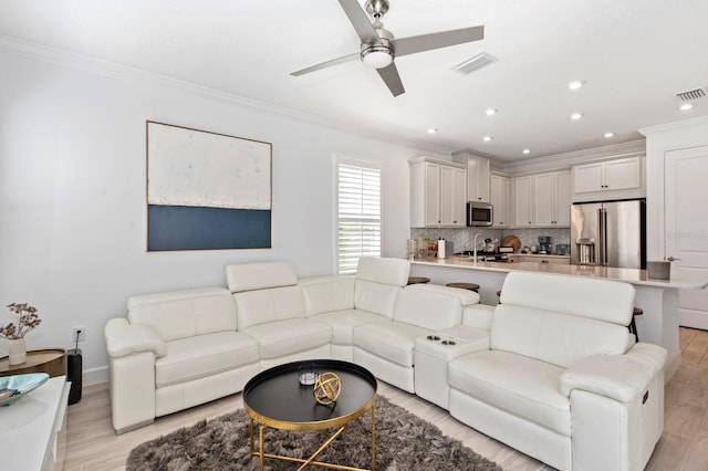 living room with ornamental molding, ceiling fan, and light hardwood / wood-style floors