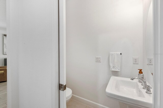 bathroom with toilet, sink, and tile patterned flooring