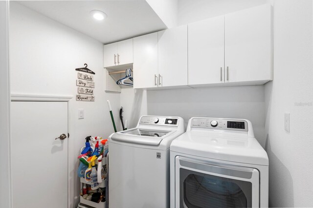 clothes washing area featuring cabinets and washer and clothes dryer