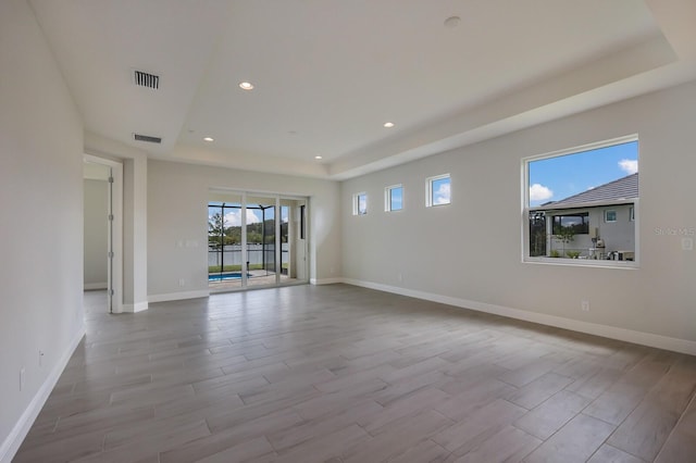 spare room featuring light hardwood / wood-style flooring and a raised ceiling