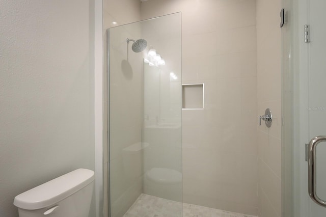 bathroom featuring walk in shower and toilet