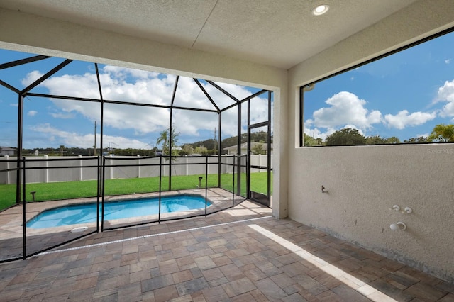 view of pool featuring a patio, glass enclosure, and a lawn