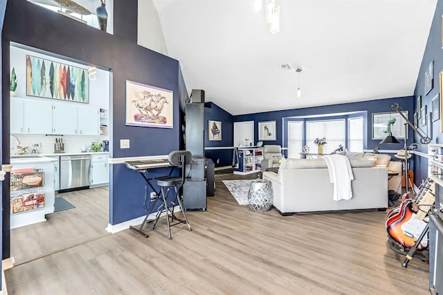 living room with sink, lofted ceiling, and light wood-type flooring