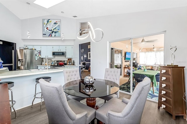 dining area featuring ceiling fan, vaulted ceiling, light hardwood / wood-style flooring, and sink