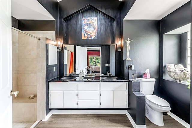 bathroom featuring tiled shower, hardwood / wood-style flooring, toilet, and vanity