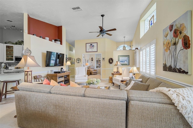 carpeted living room with a towering ceiling and ceiling fan