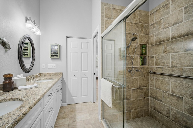 bathroom featuring a shower with shower door, double vanity, and tile patterned flooring