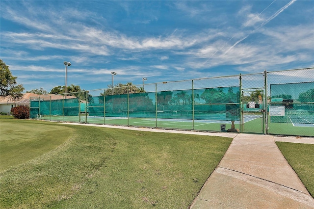 view of tennis court featuring a yard