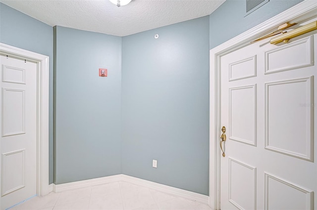 interior space featuring light tile patterned floors and a textured ceiling