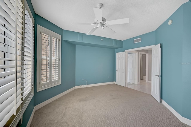 unfurnished bedroom with ceiling fan, light colored carpet, and a textured ceiling