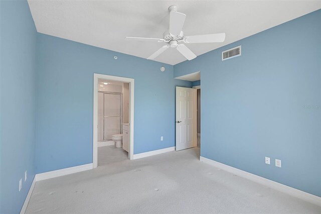 unfurnished bedroom featuring ceiling fan, ensuite bathroom, and light colored carpet