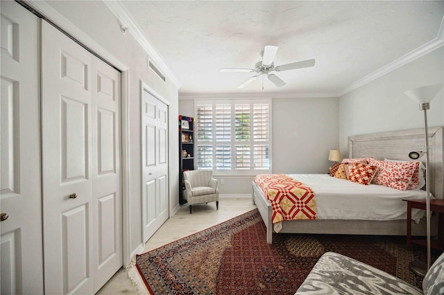 bedroom featuring multiple closets, crown molding, and ceiling fan