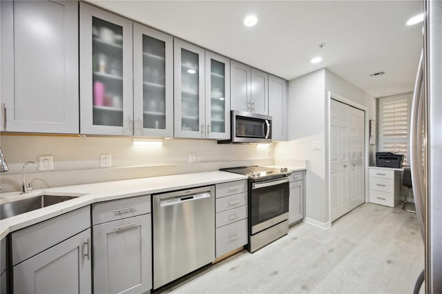 kitchen featuring light hardwood / wood-style flooring, gray cabinets, stainless steel appliances, and sink