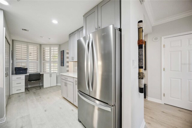 kitchen with gray cabinetry, light hardwood / wood-style flooring, ornamental molding, and stainless steel refrigerator