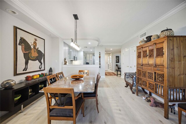 dining space with ornamental molding and light wood-type flooring