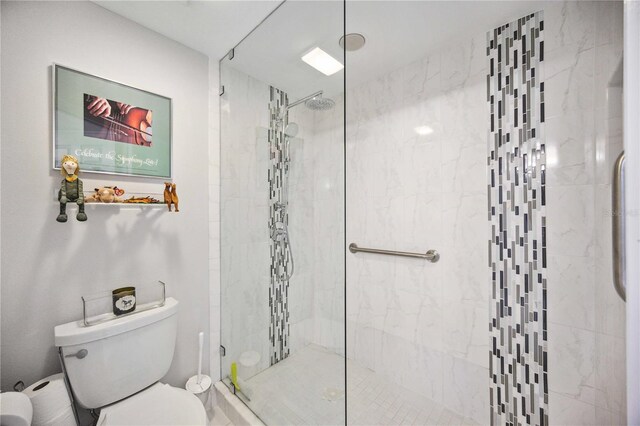 bathroom featuring a shower with shower door and toilet